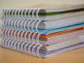 NIFA Reports. Photo of four stacked binders with sheets of paper and folders; courtesy of Pixabay.